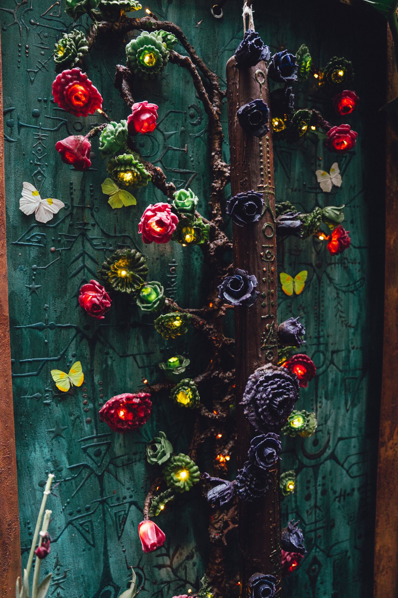 Árbol de la memoria: sculpted wax roses climbing a carved tree panel