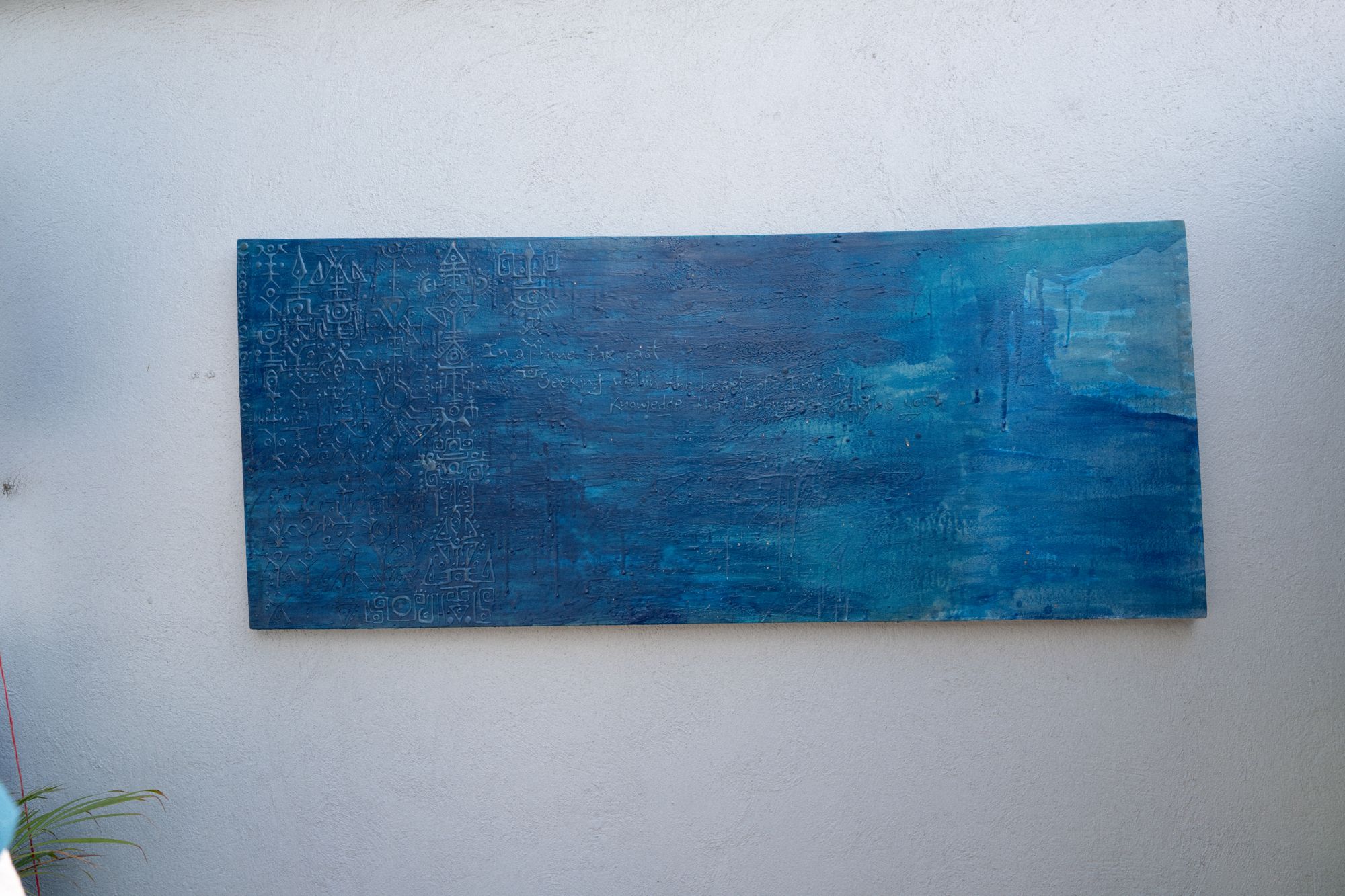 Lenguaje I: large blue relief painting on a sunlit rooftop wall