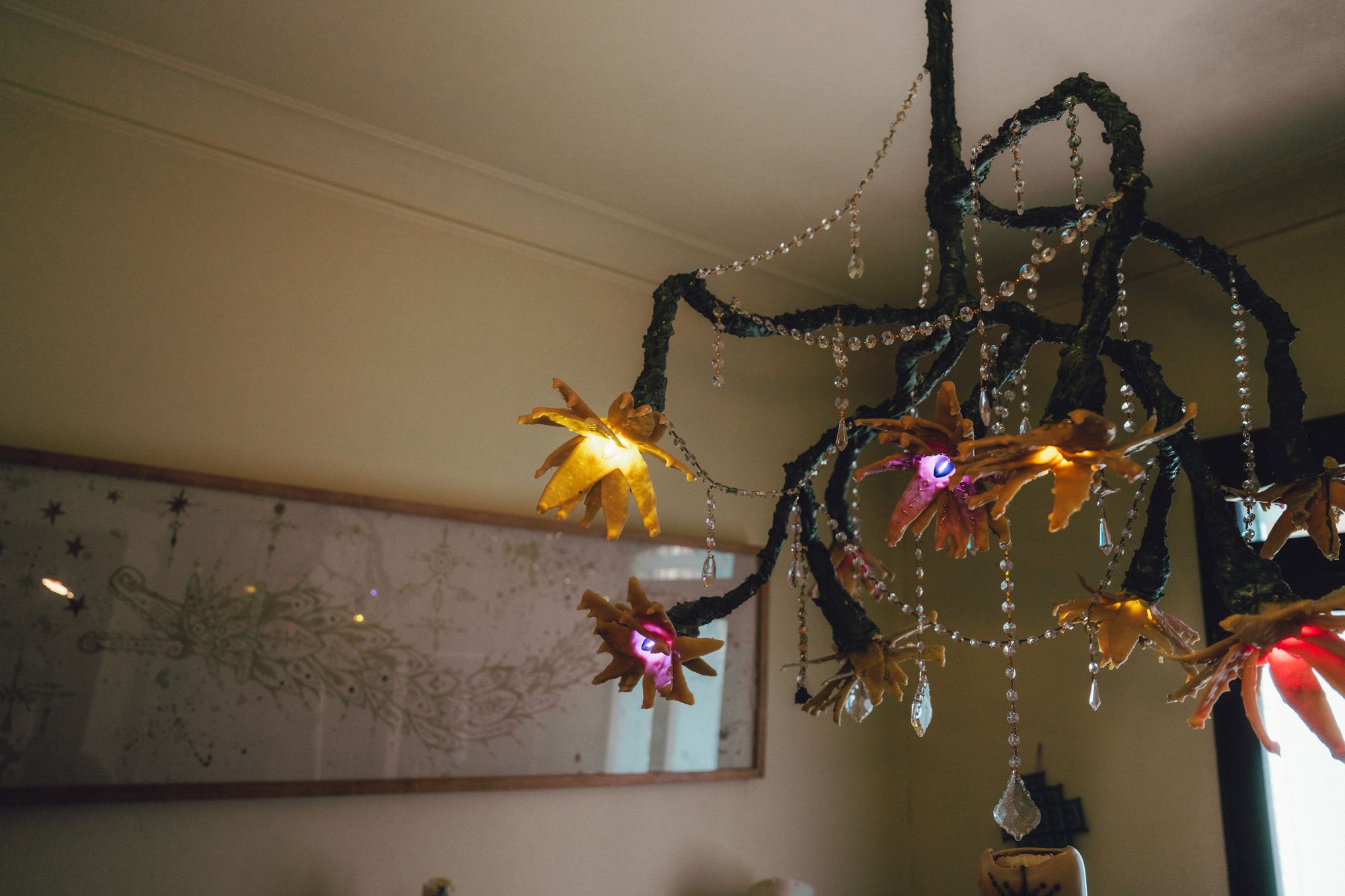 Especie Nocturna I: botanical chandelier of dark branches, crystal strands, and glowing wax flowers