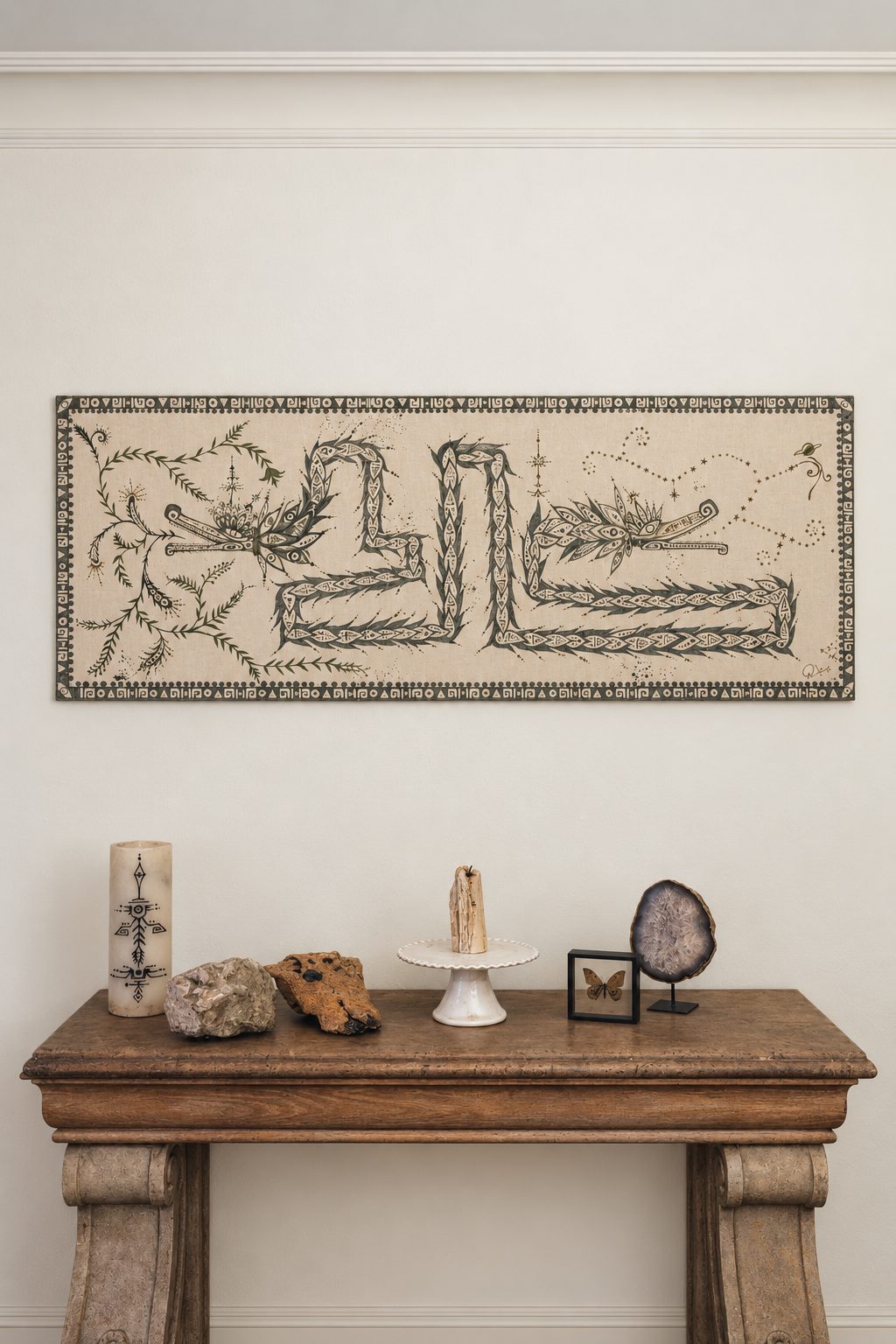 Horizontal canvas painted with vine and glyph forms shaped like a serpent, framed and hung on a wall